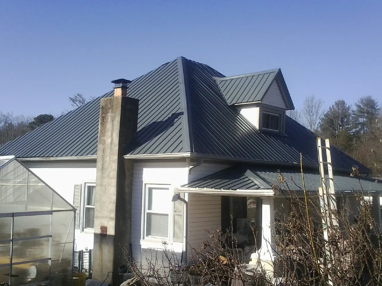 Dark blue standing seam metal roof on a white farmhouse with dormer — Slate & Tile Roof Repair by Roofing Brothers in Hancock