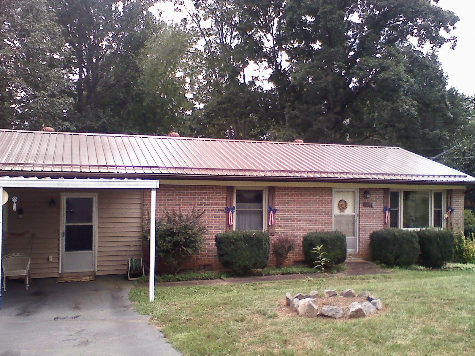 Bronze metal roof and carport on a brick ranch home — Roof Repair work by our crew in Hancock
